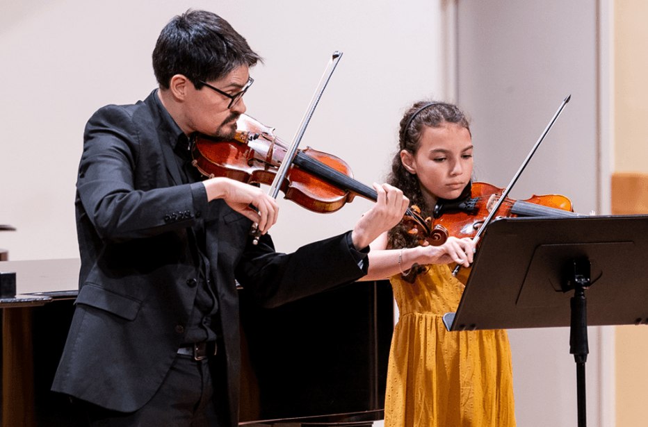 private violin teacher giving in-person lesson to student